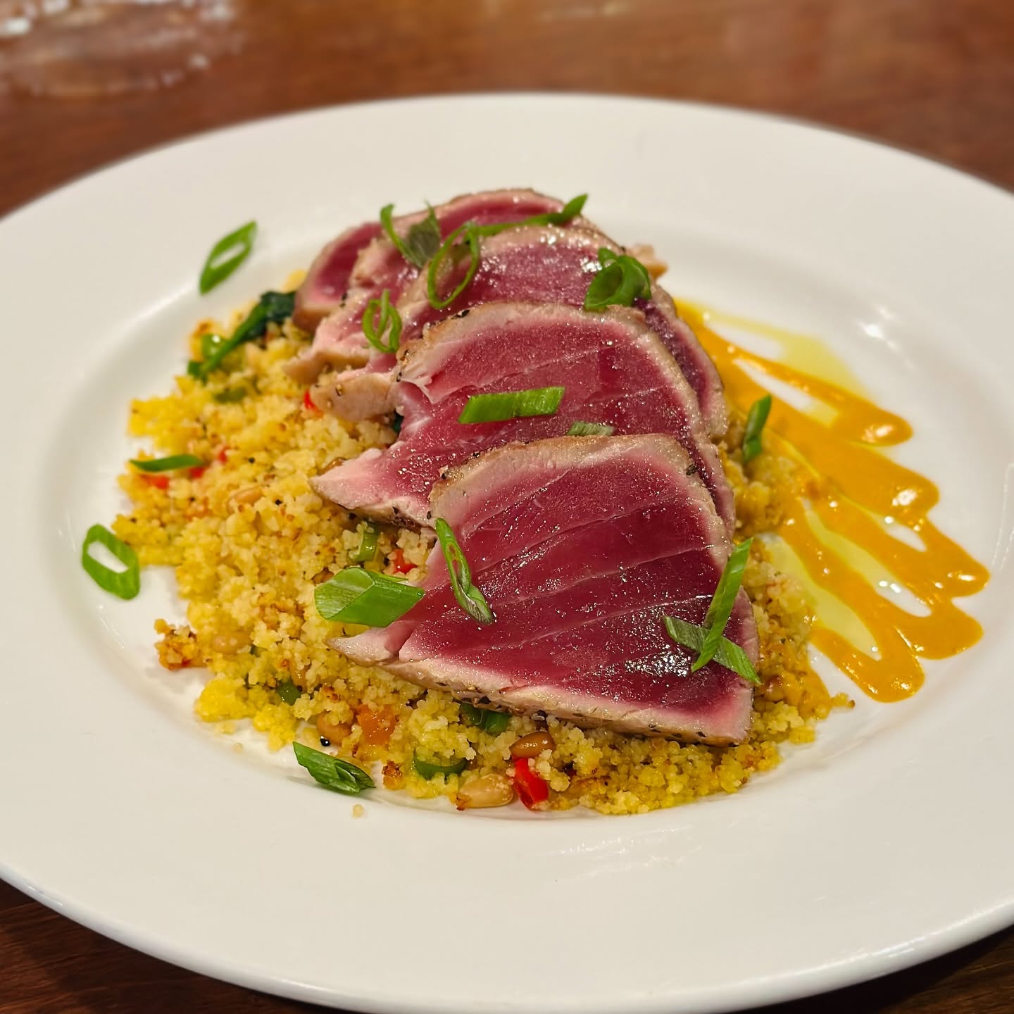 Seared rare tuna slices over couscous with a mango sauce