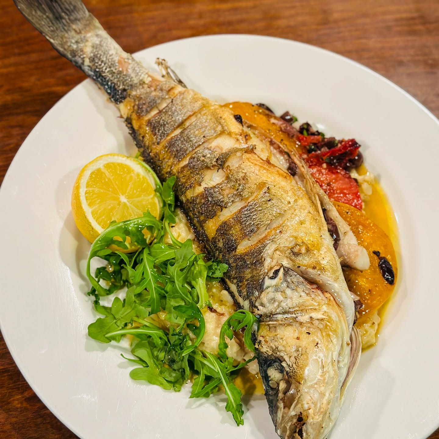 A whole roasted fish with lemon and arugula