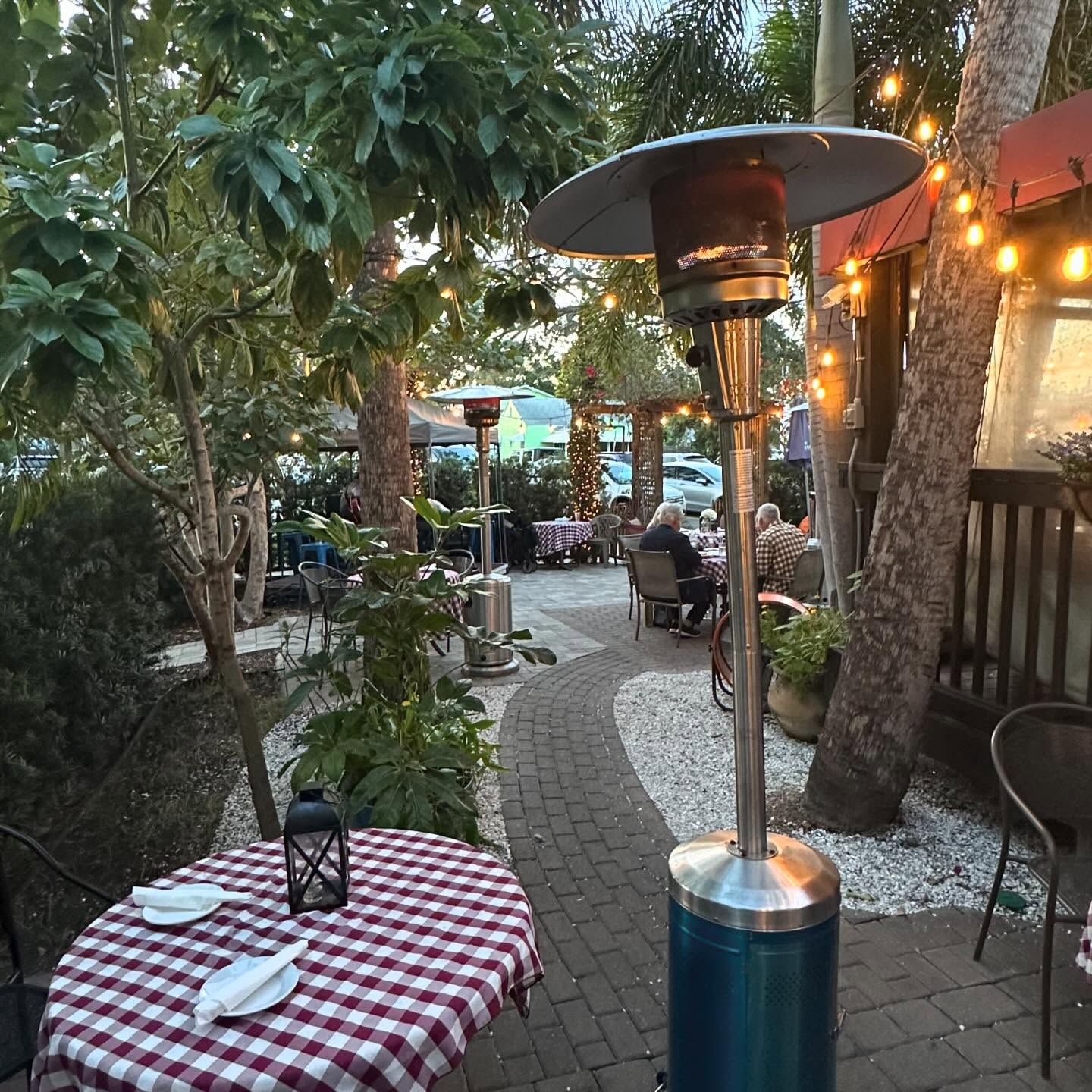 A lantern-lit gingham table under the Veranda's string lights
