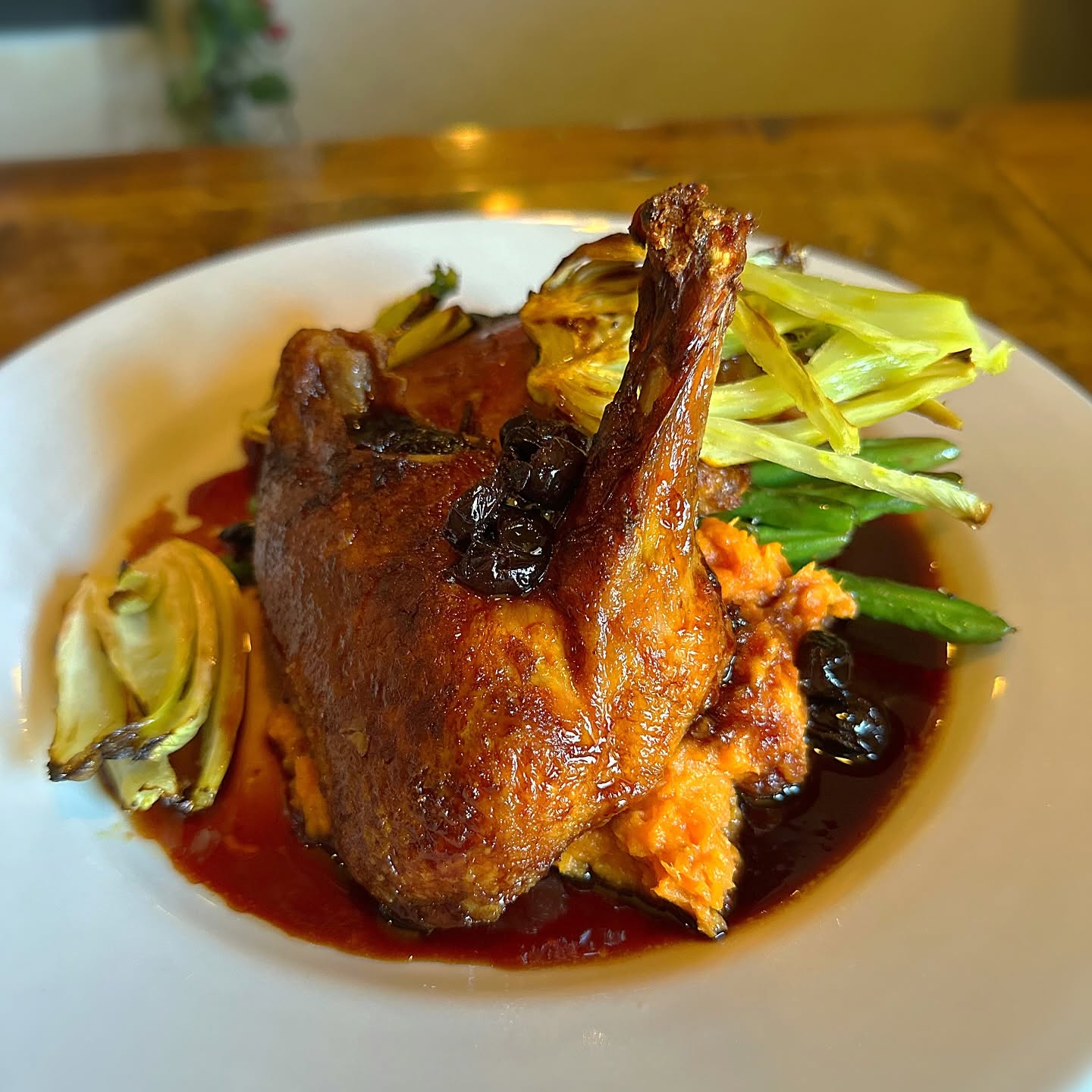 A roasted duck leg in a dark berry sauce