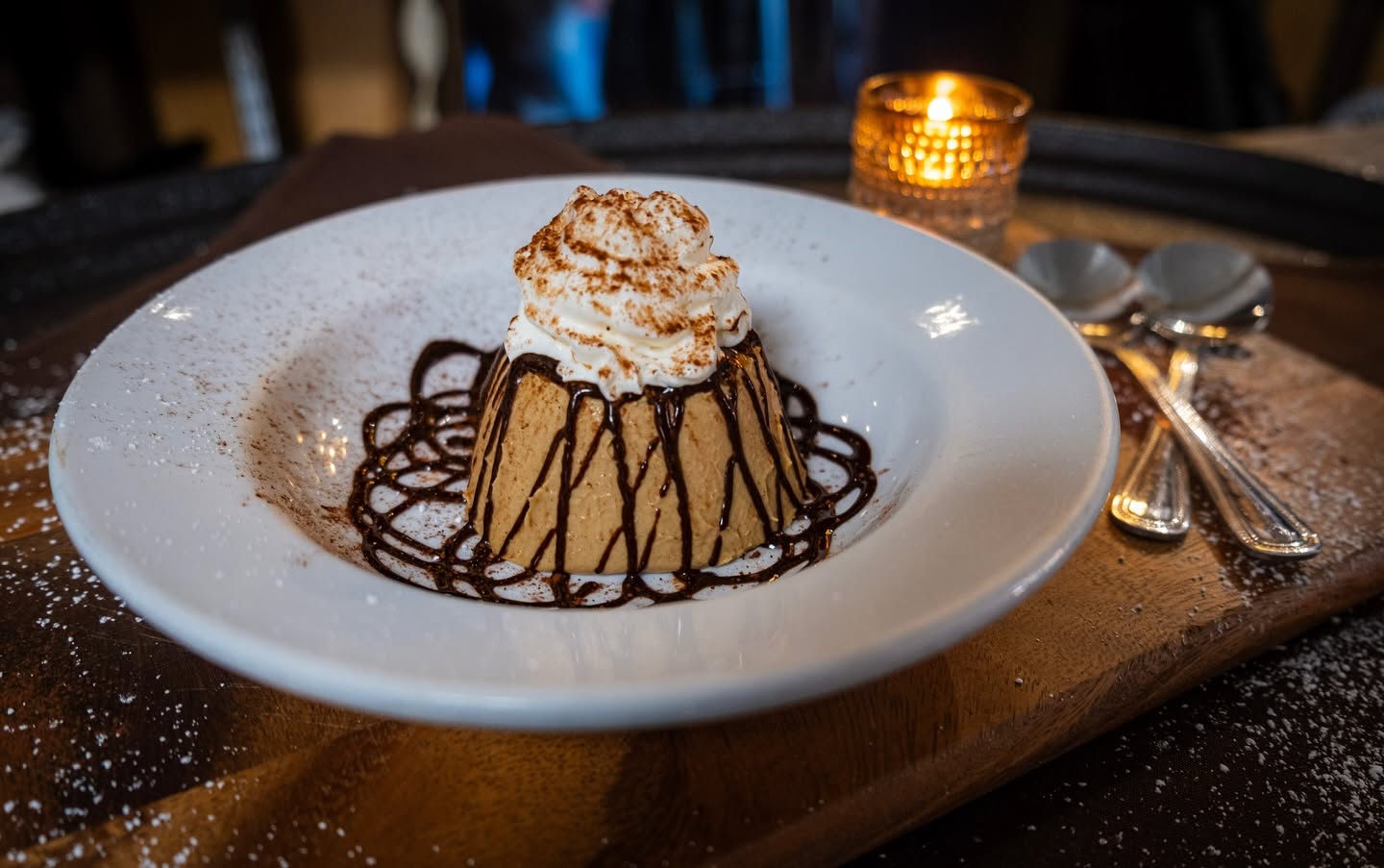 A chocolate dessert with whipped cream beside a candle