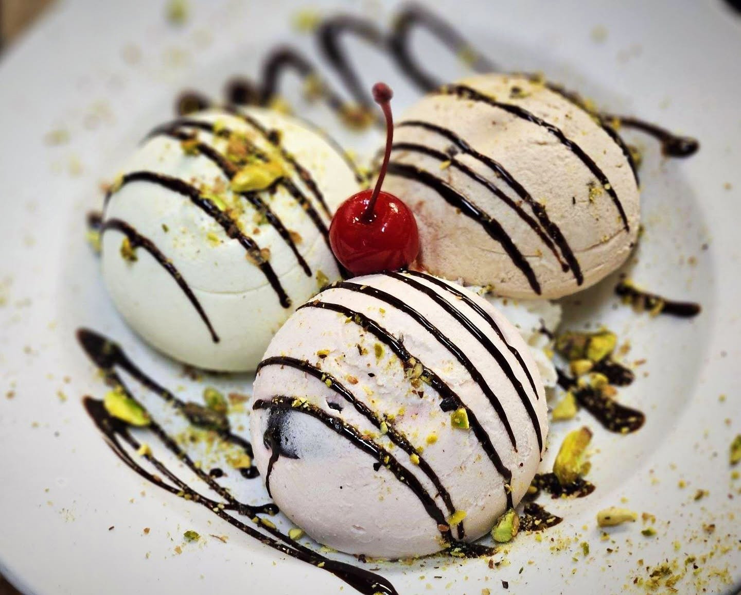 Chocolate-drizzled meringues with a cherry, made in house