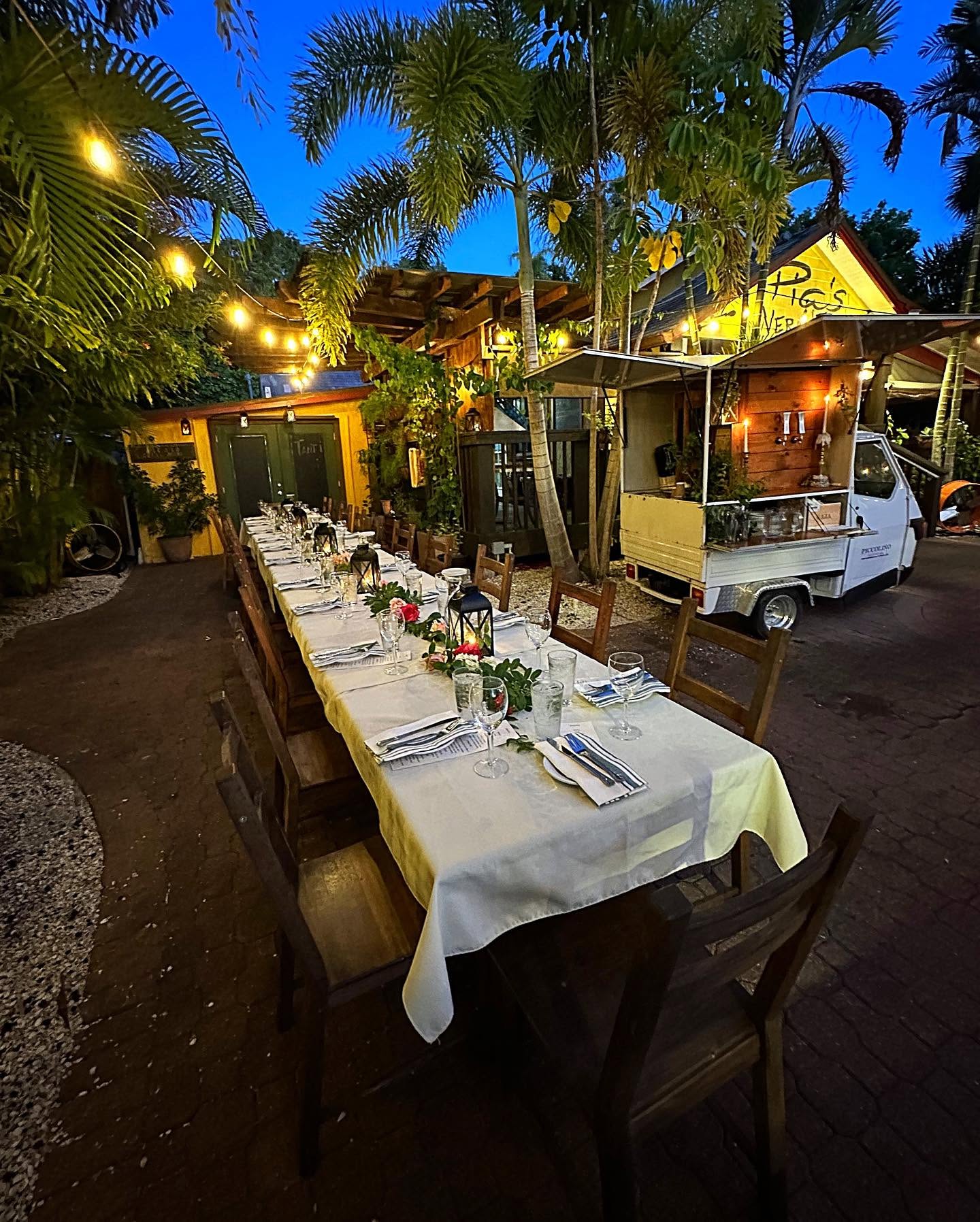 A long white-clothed table set down the garden path under string lights