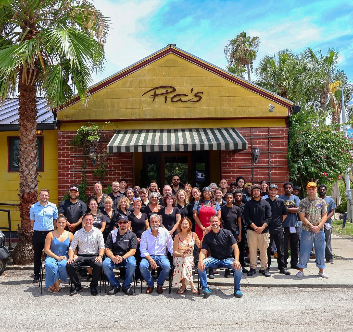 The Trattoria's yellow front on Beach Blvd S with the whole staff gathered outside