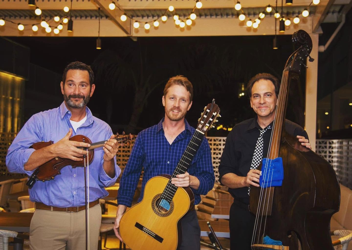 Three musicians with mandolin, guitar and upright bass under the Veranda's string lights