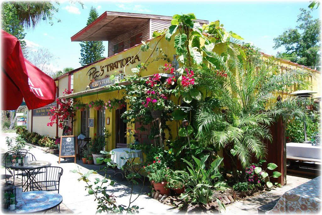 The Trattoria's yellow front framed by flowering vines on Beach Blvd S