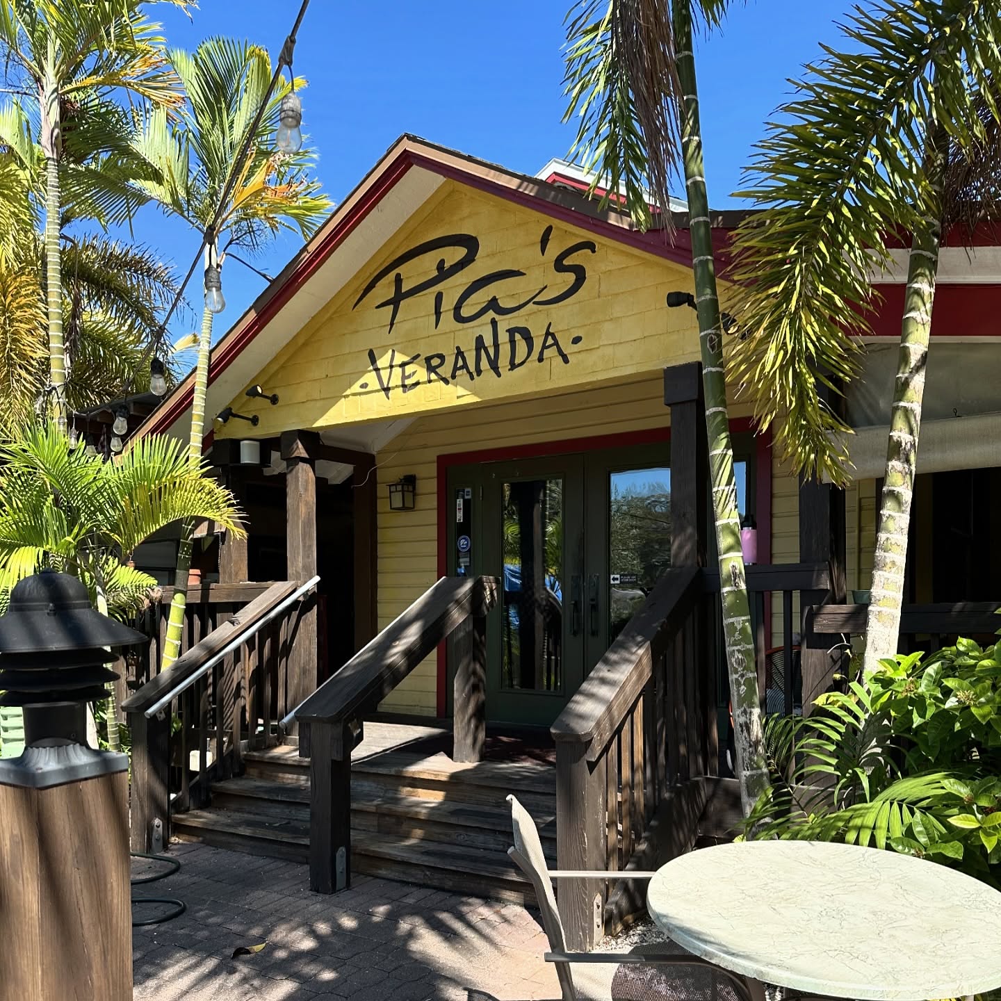 The front steps of Pia's Veranda under palms on a sunny afternoon