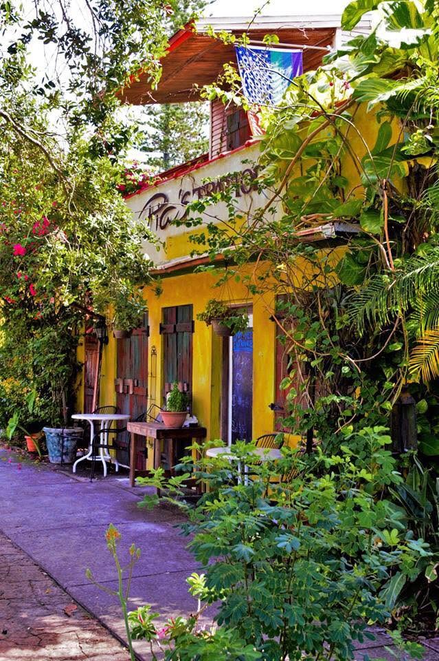 The Trattoria's yellow front half-hidden by flowering vines, sidewalk tables beside the door