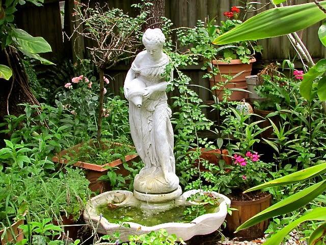 A stone statue fountain among ferns in the Veranda garden
