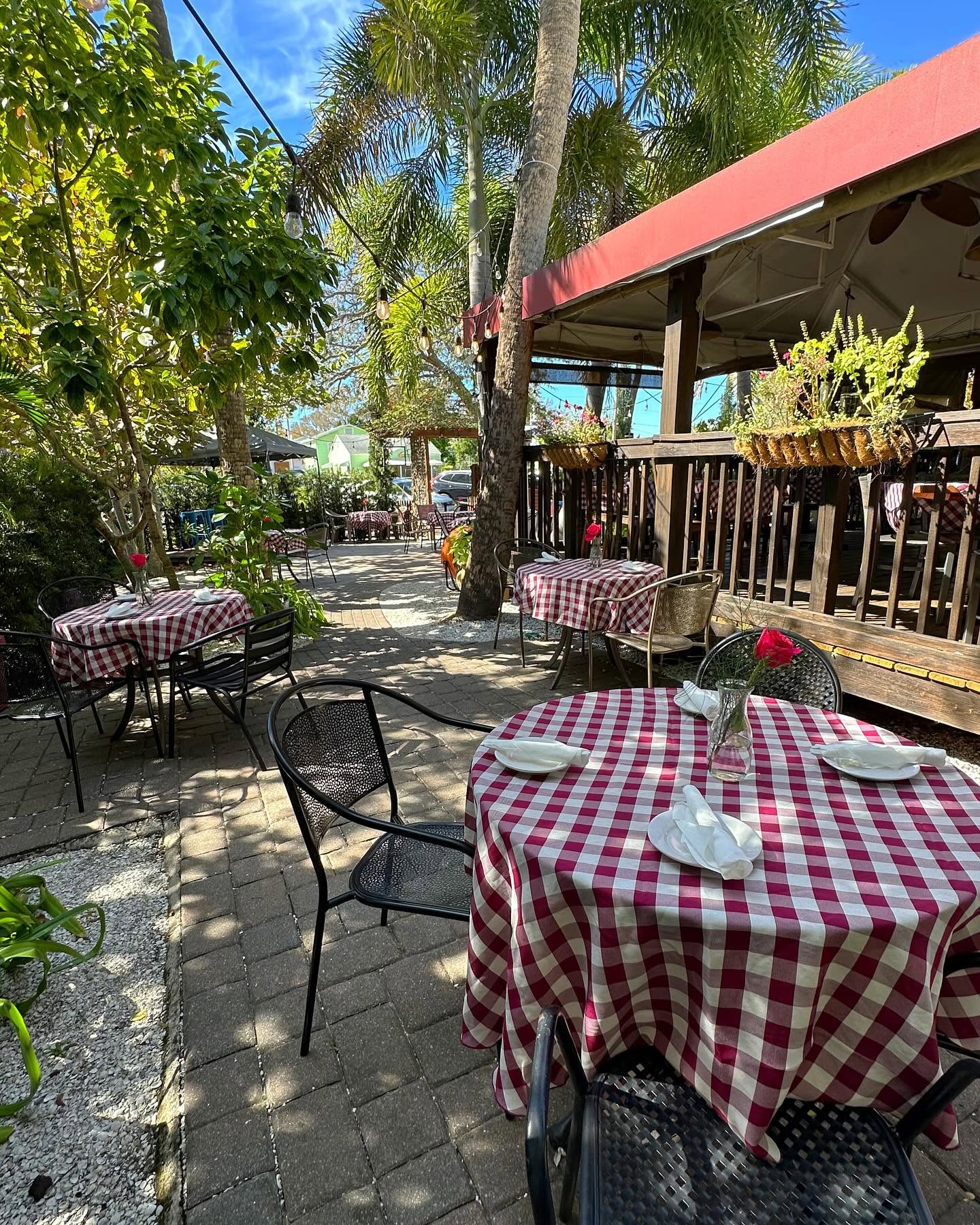Gingham tables along the Veranda's garden path in afternoon sun