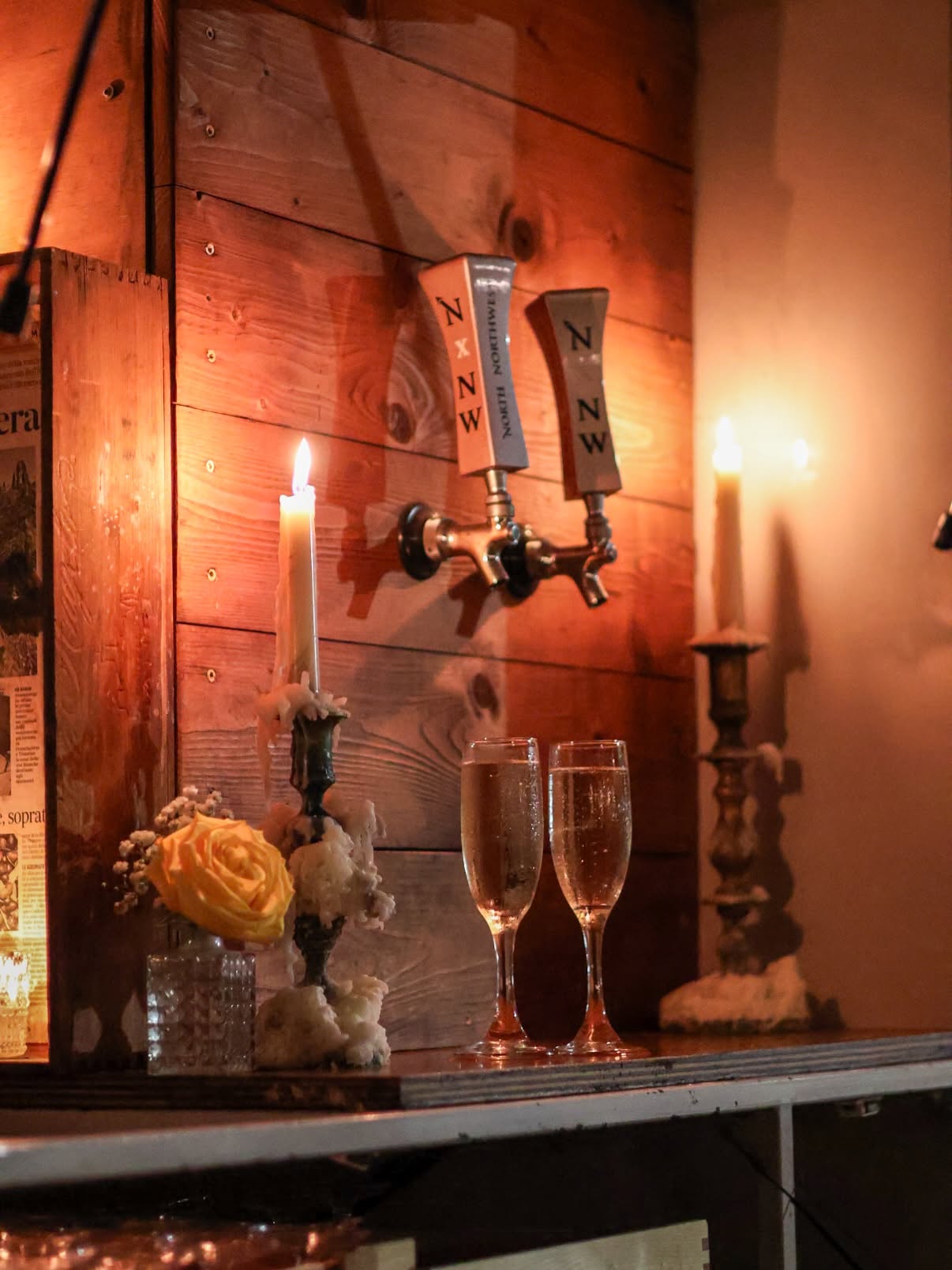 Candles and a pair of champagne flutes against a weathered wood wall