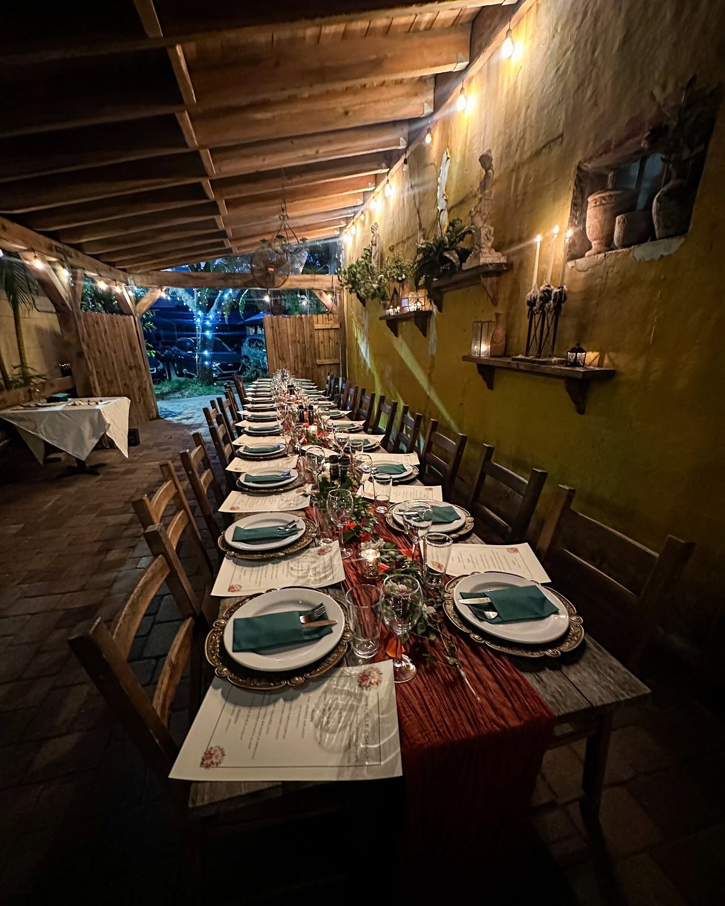 A long table set for a private dinner by candlelight beneath the Trattoria's covered patio roof