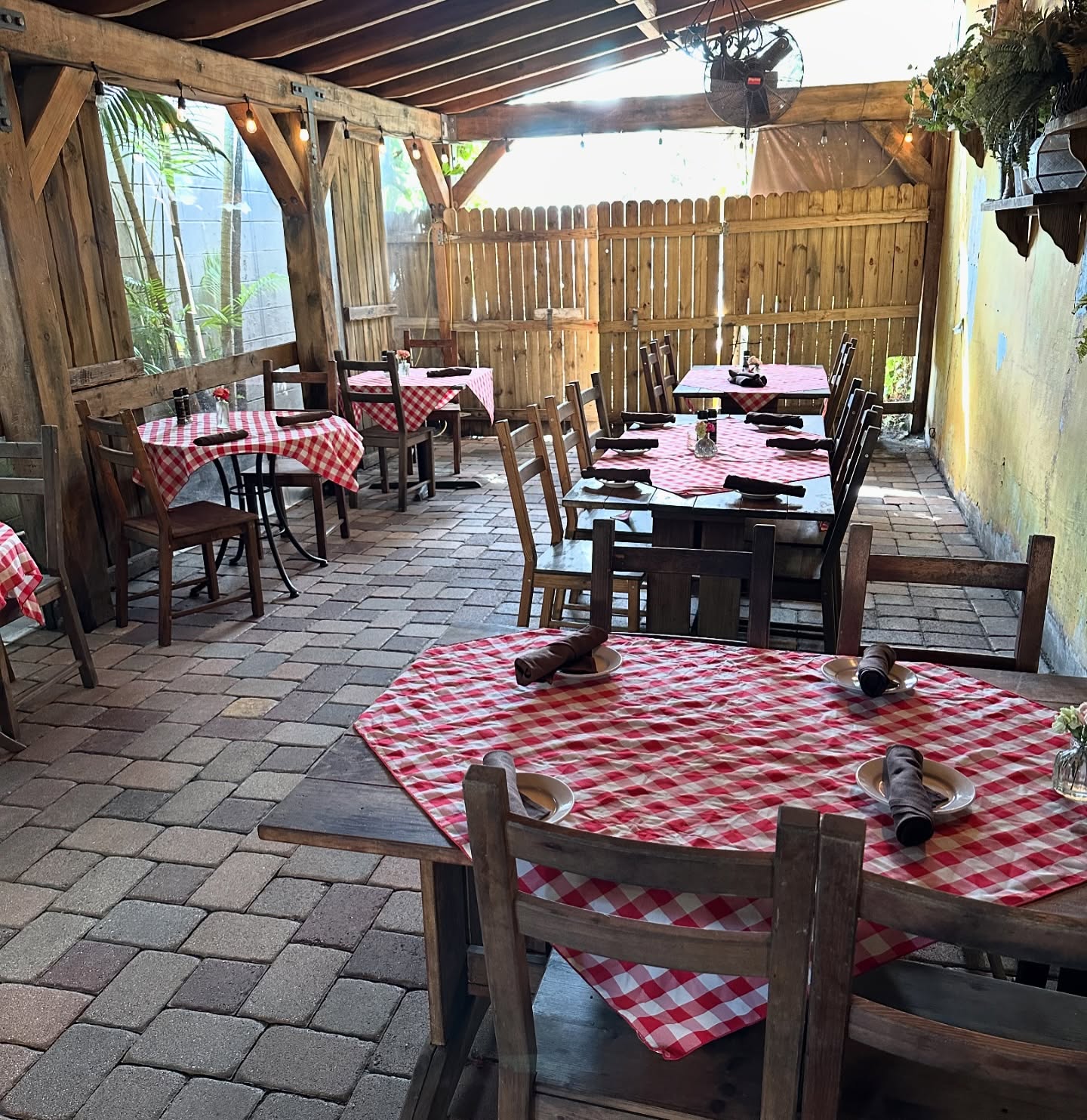 Red checked tables on the brick floor of the covered patio at Pia's Trattoria