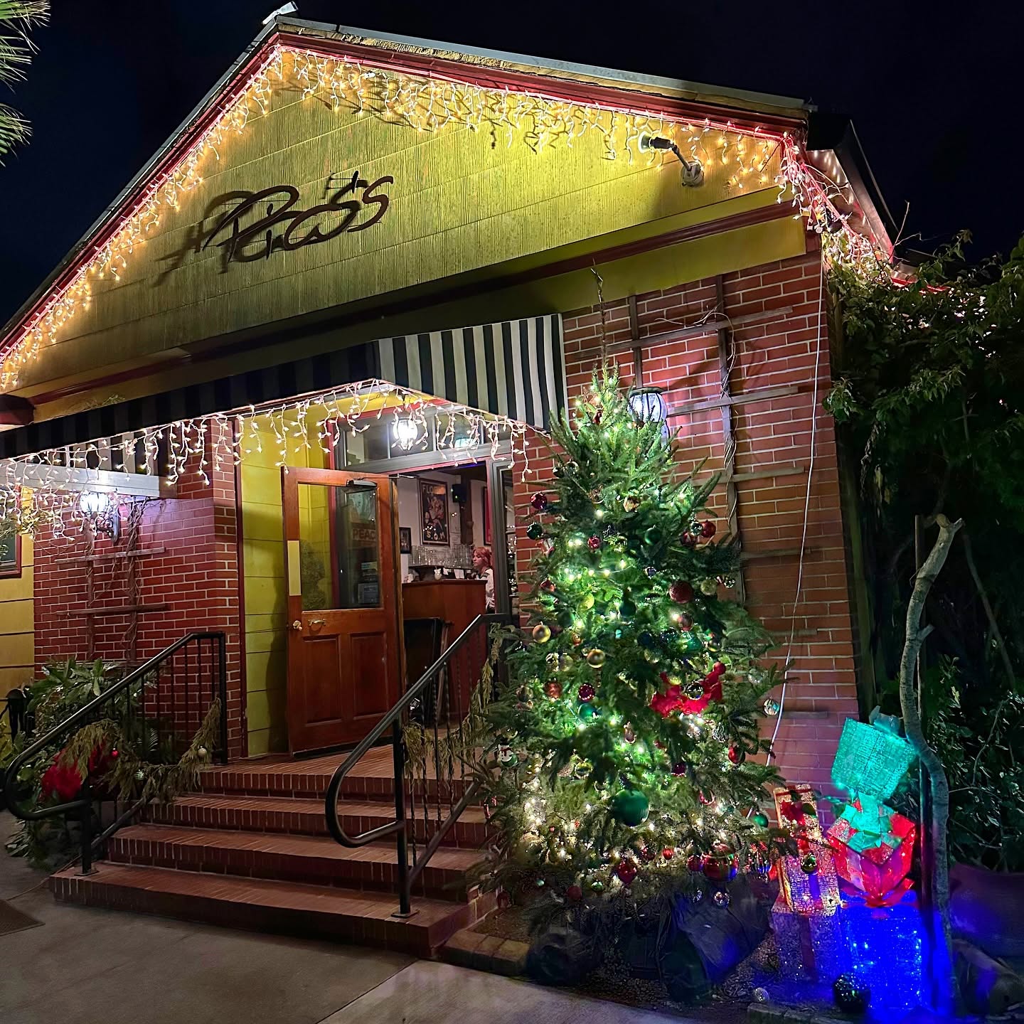 The Trattoria's front steps at night, strung with holiday lights and a decorated tree
