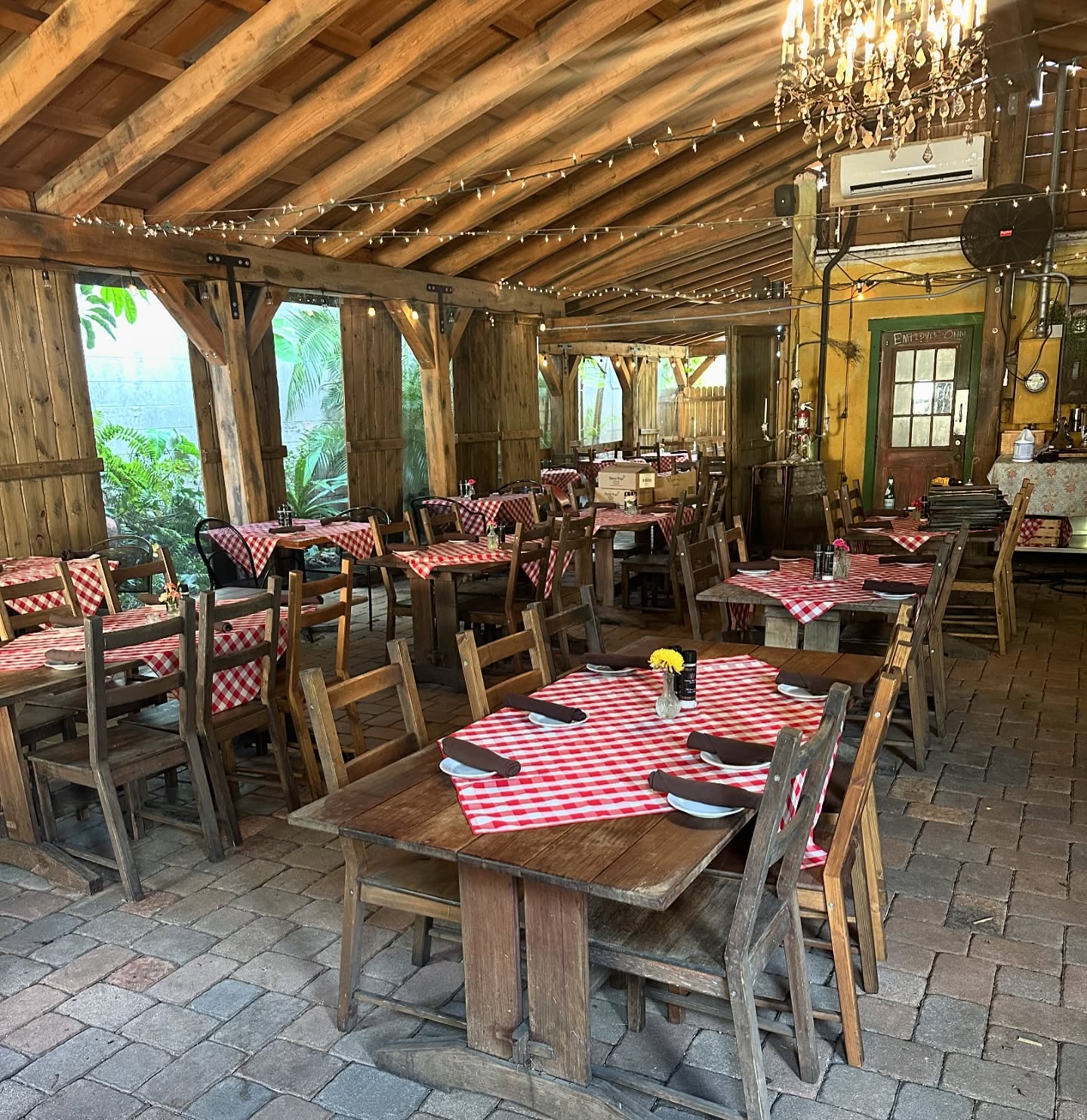 Gingham tables under the timber roof of the covered patio at Pia's Trattoria