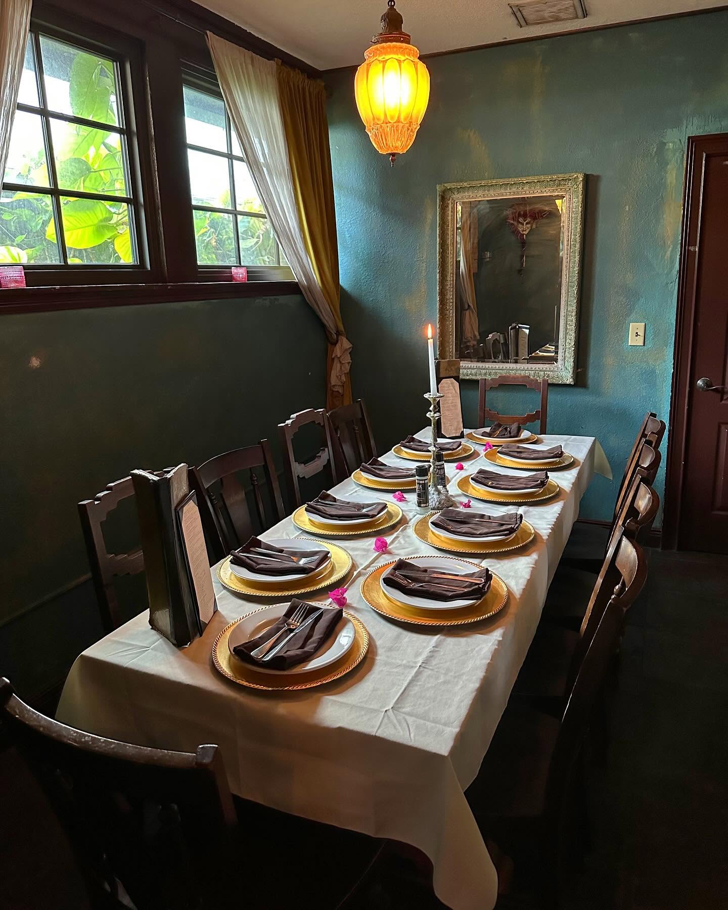 The teal-walled private room set for dinner, a candle in the window at Pia's Trattoria