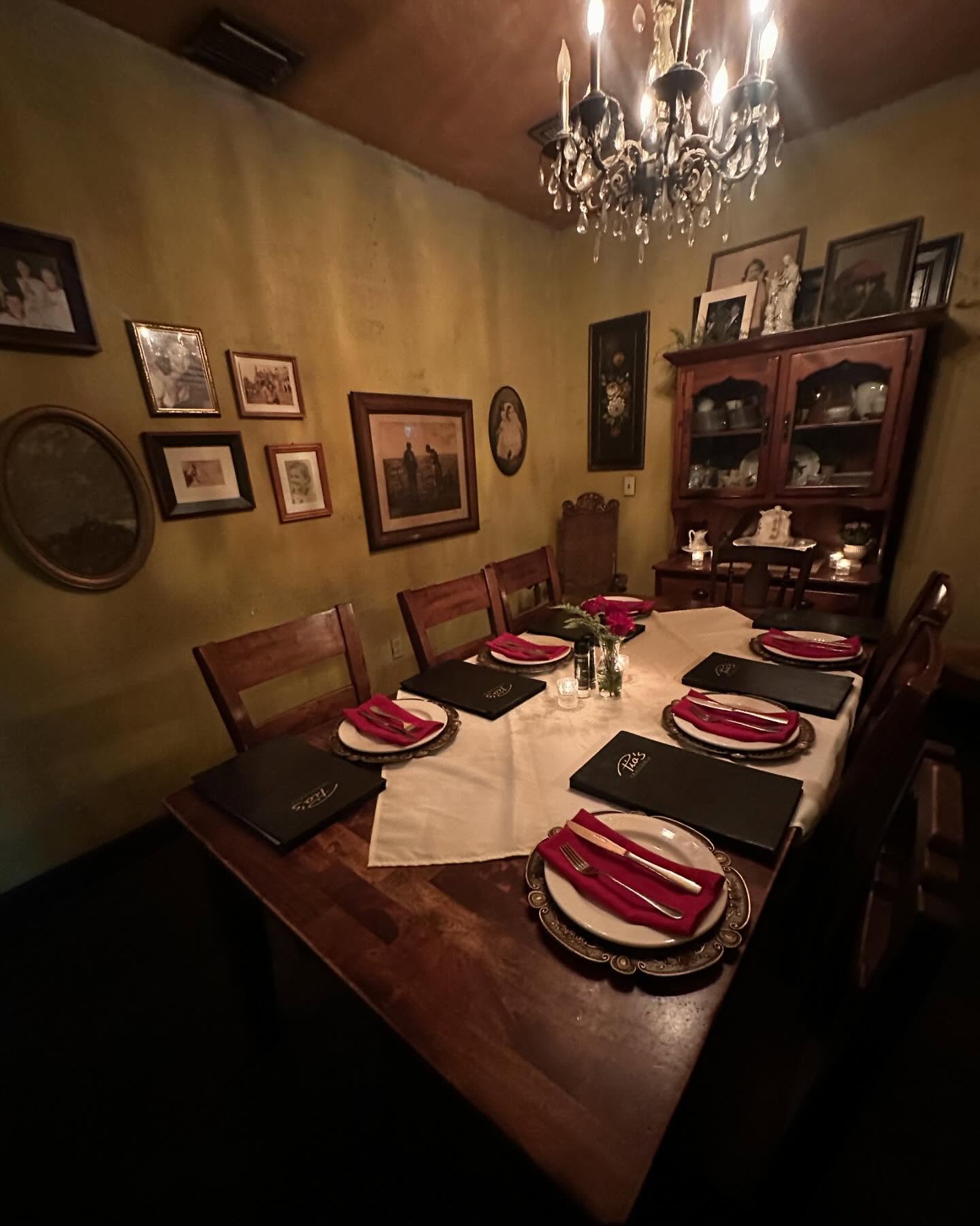 The Trattoria's chandelier dining room, tables set with red napkins and framed pictures on yellow walls