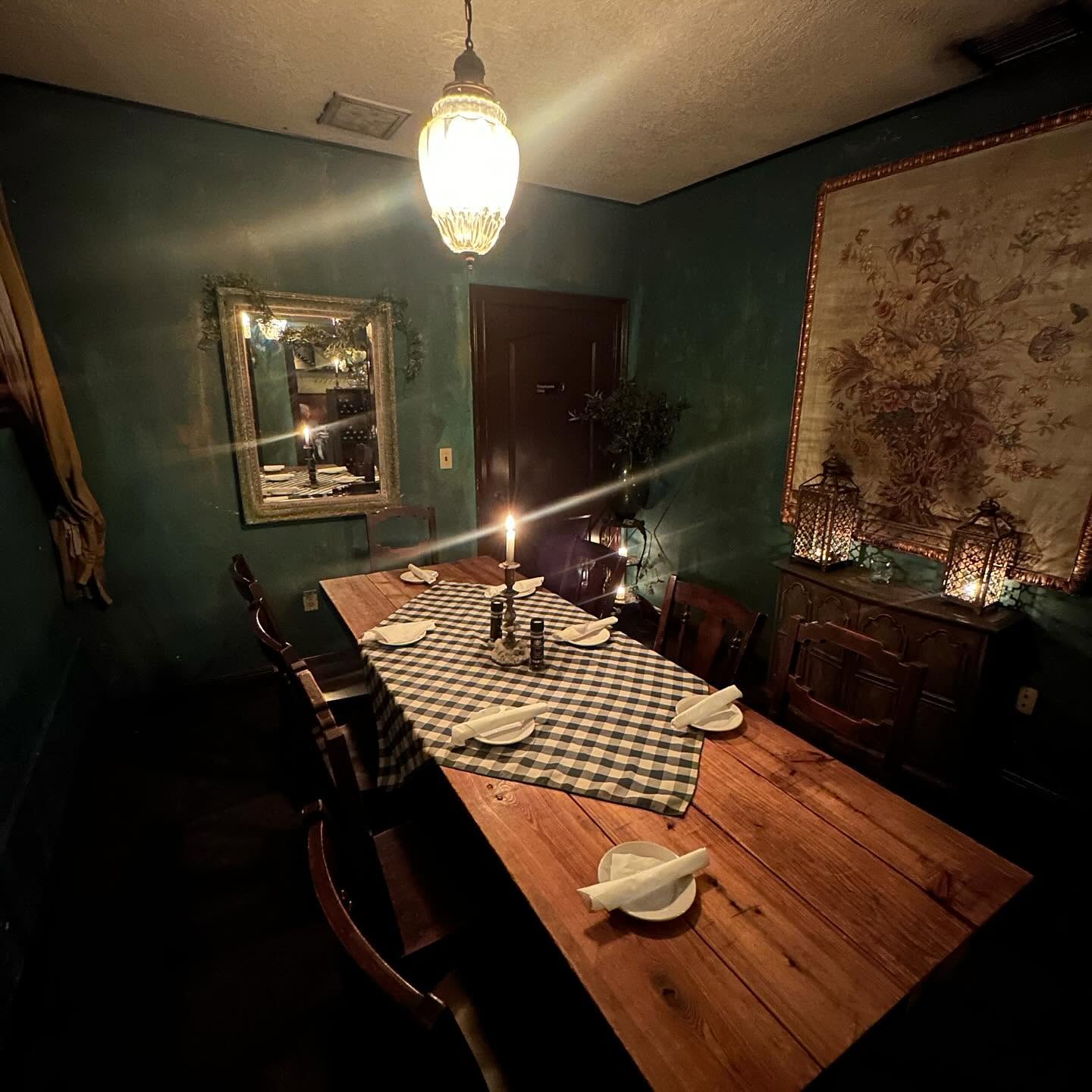 A checked runner and a single candle on a long wooden table in the Trattoria's teal room