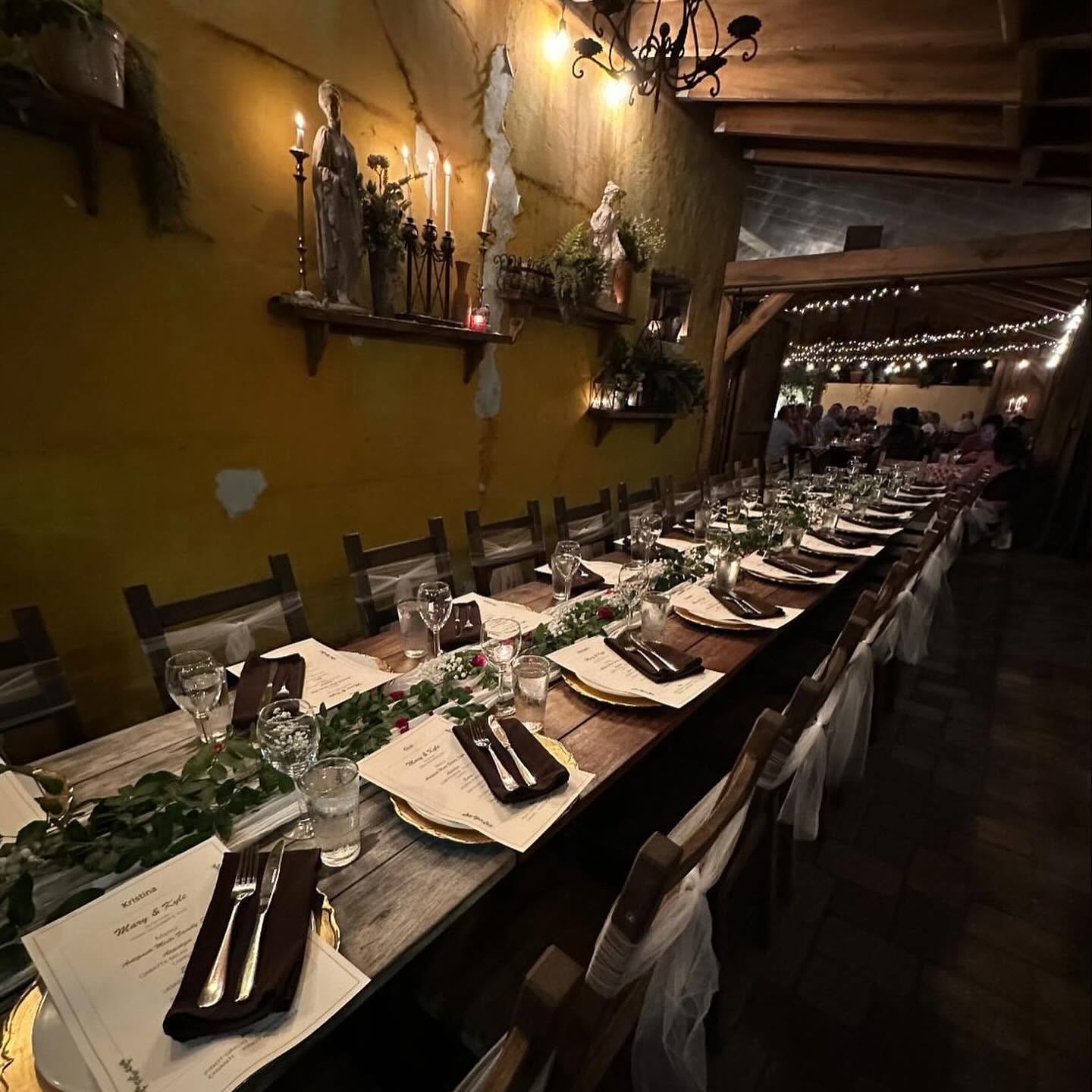 A long table with greenery beneath the patio's yellow walls