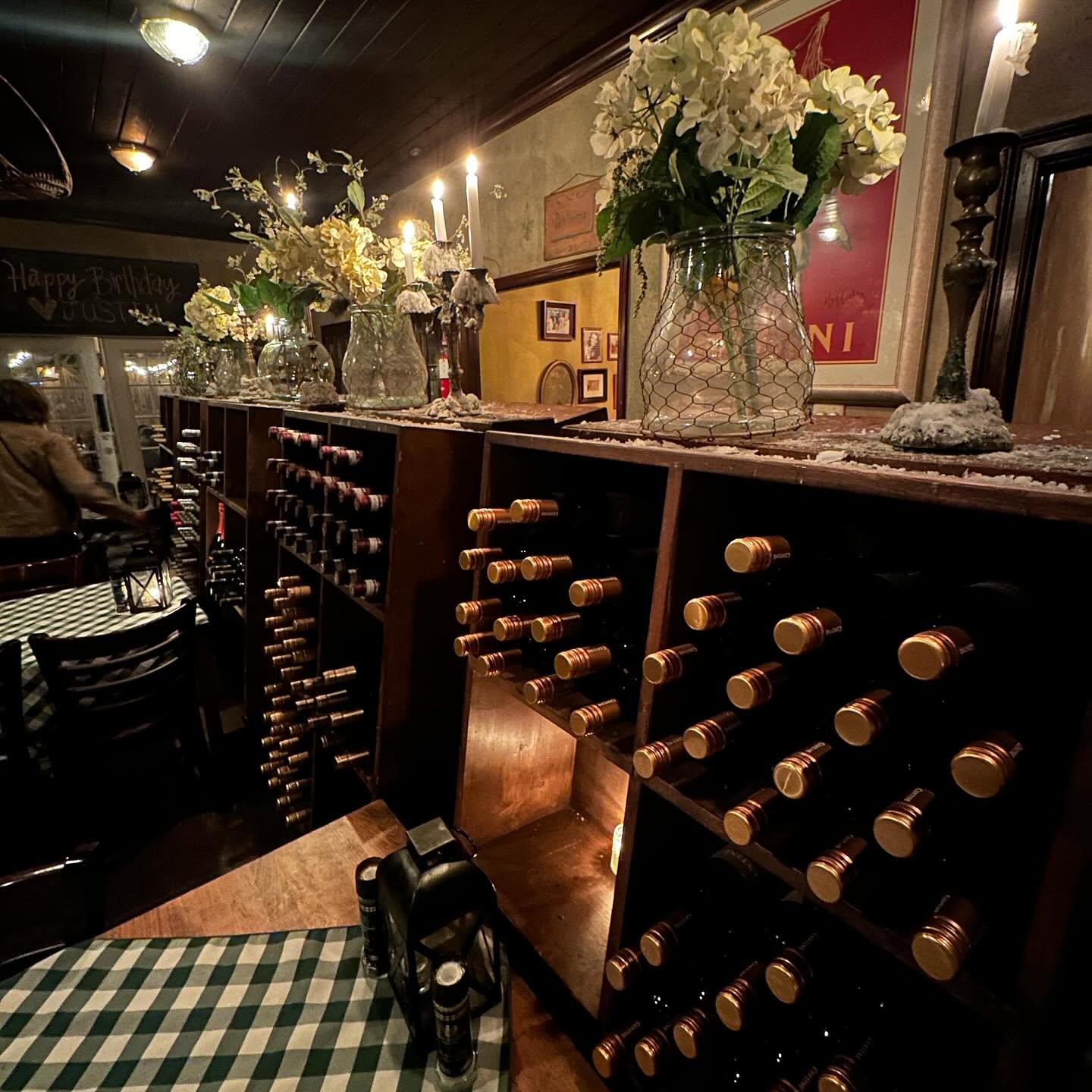 The wine-rack wall with hydrangeas and candles at Pia's Trattoria