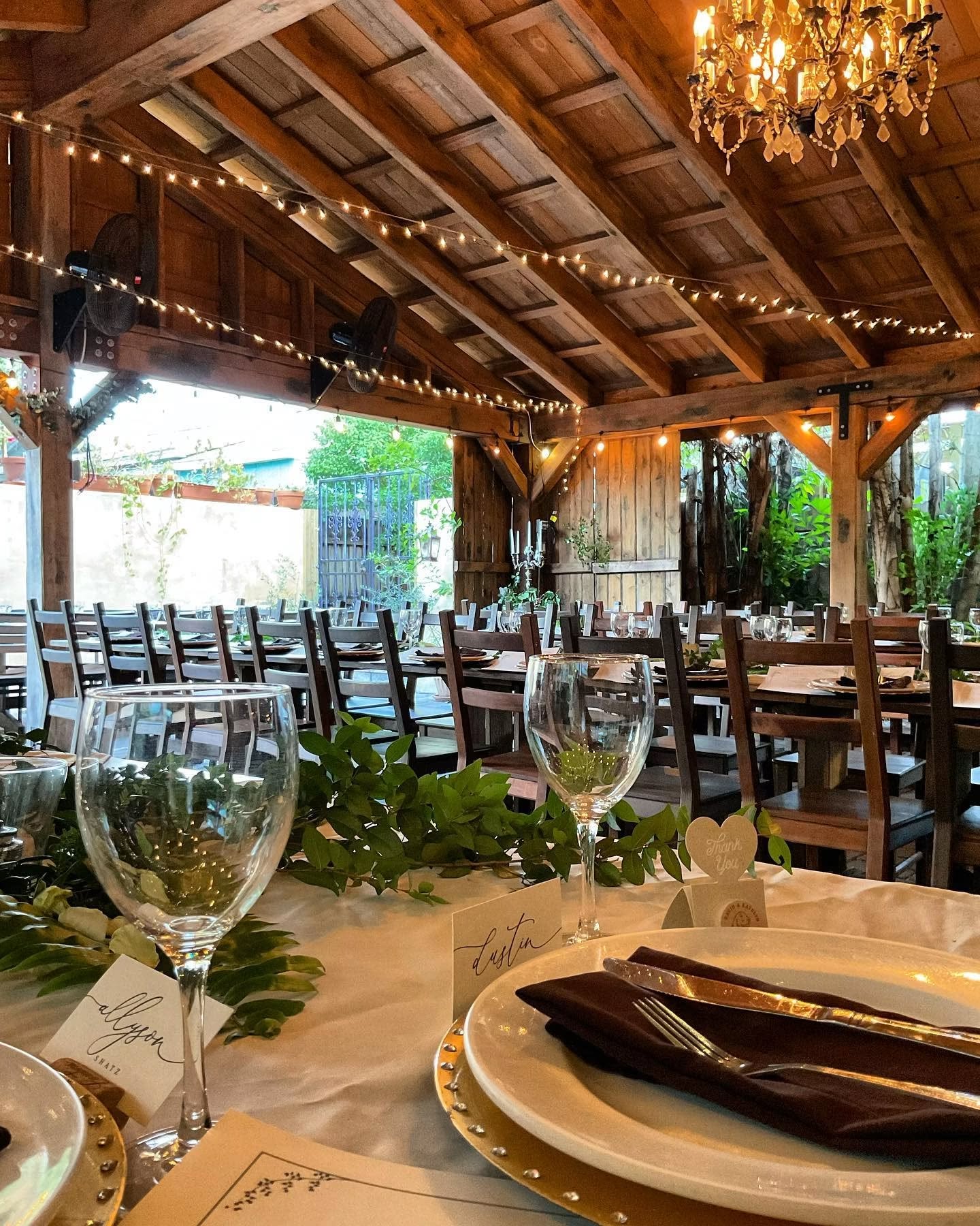 Place settings with greenery under the patio chandelier