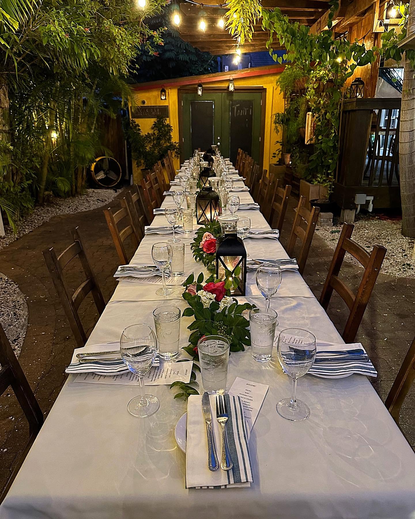 A long white table set in the Veranda garden for a private dinner