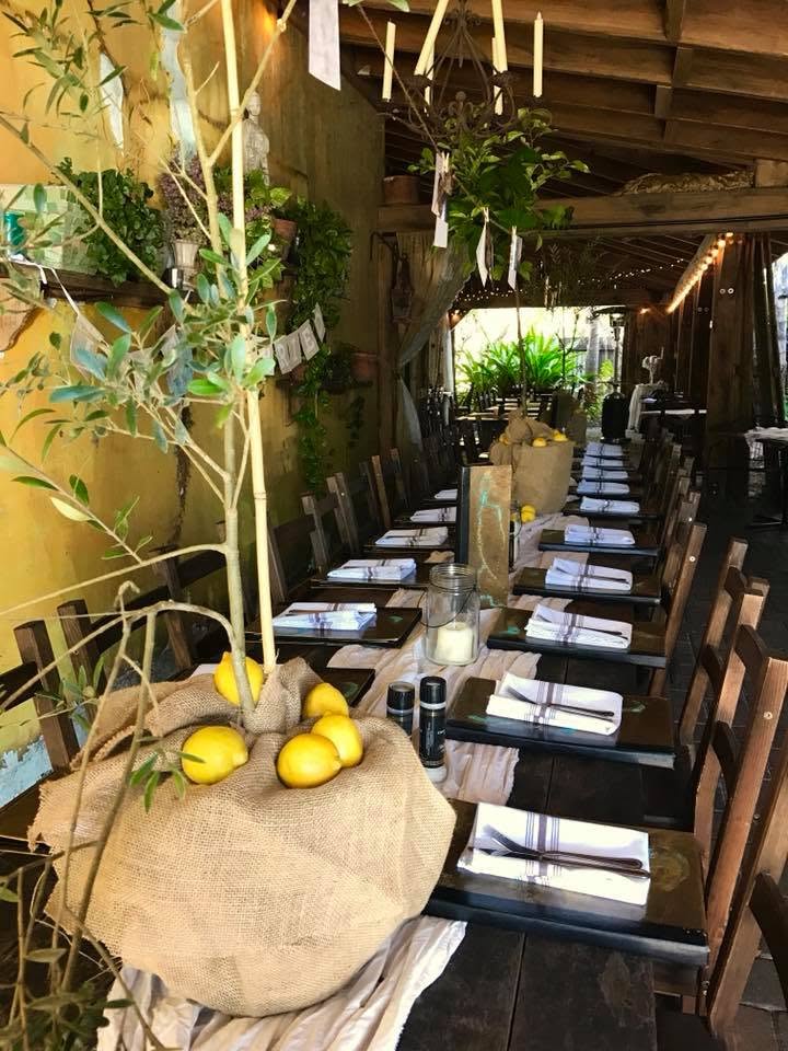 A long candlelit table with lemons and greenery down the covered patio