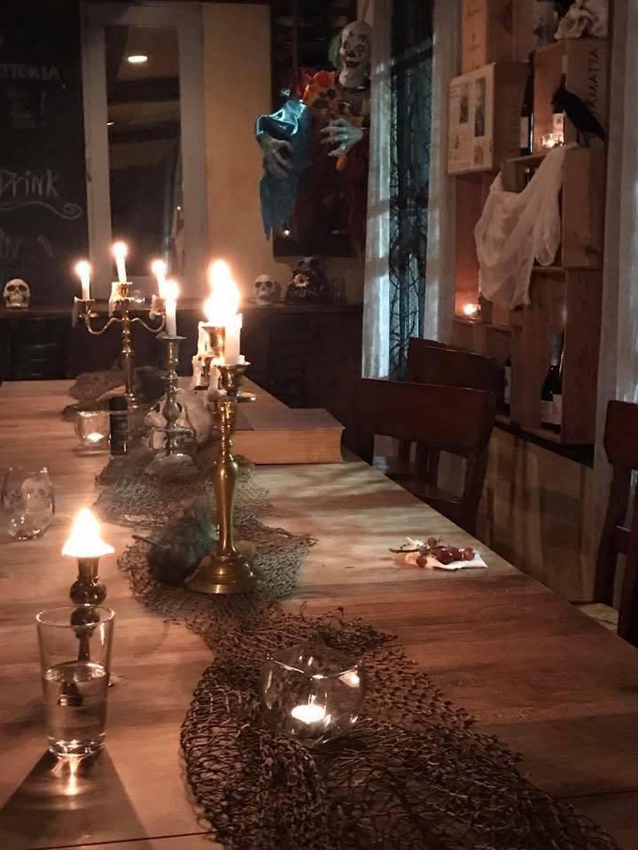 A candelabra-lit long table dressed for a Halloween dinner at the Trattoria