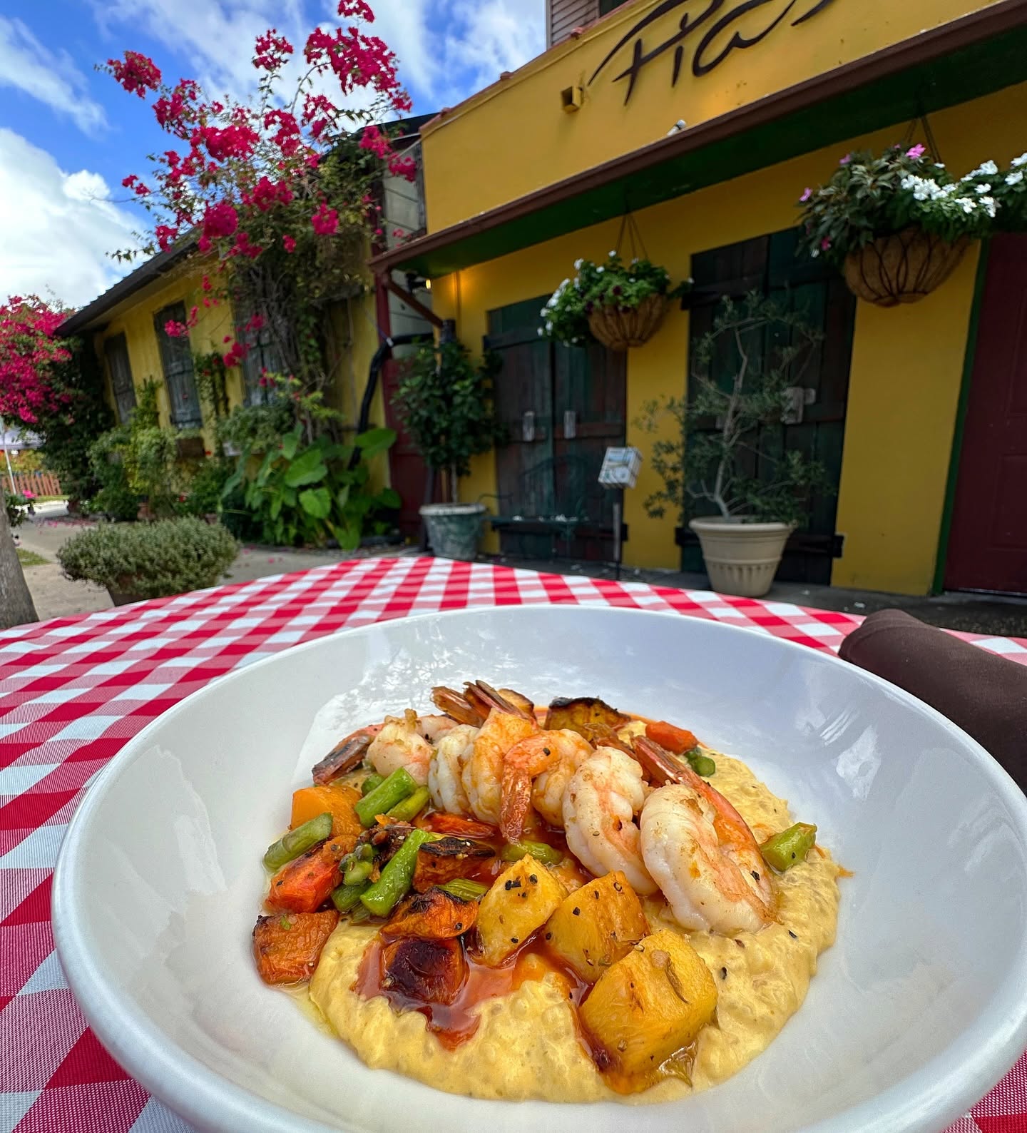 Shrimp over polenta with roasted squash on a gingham table outside the Trattoria