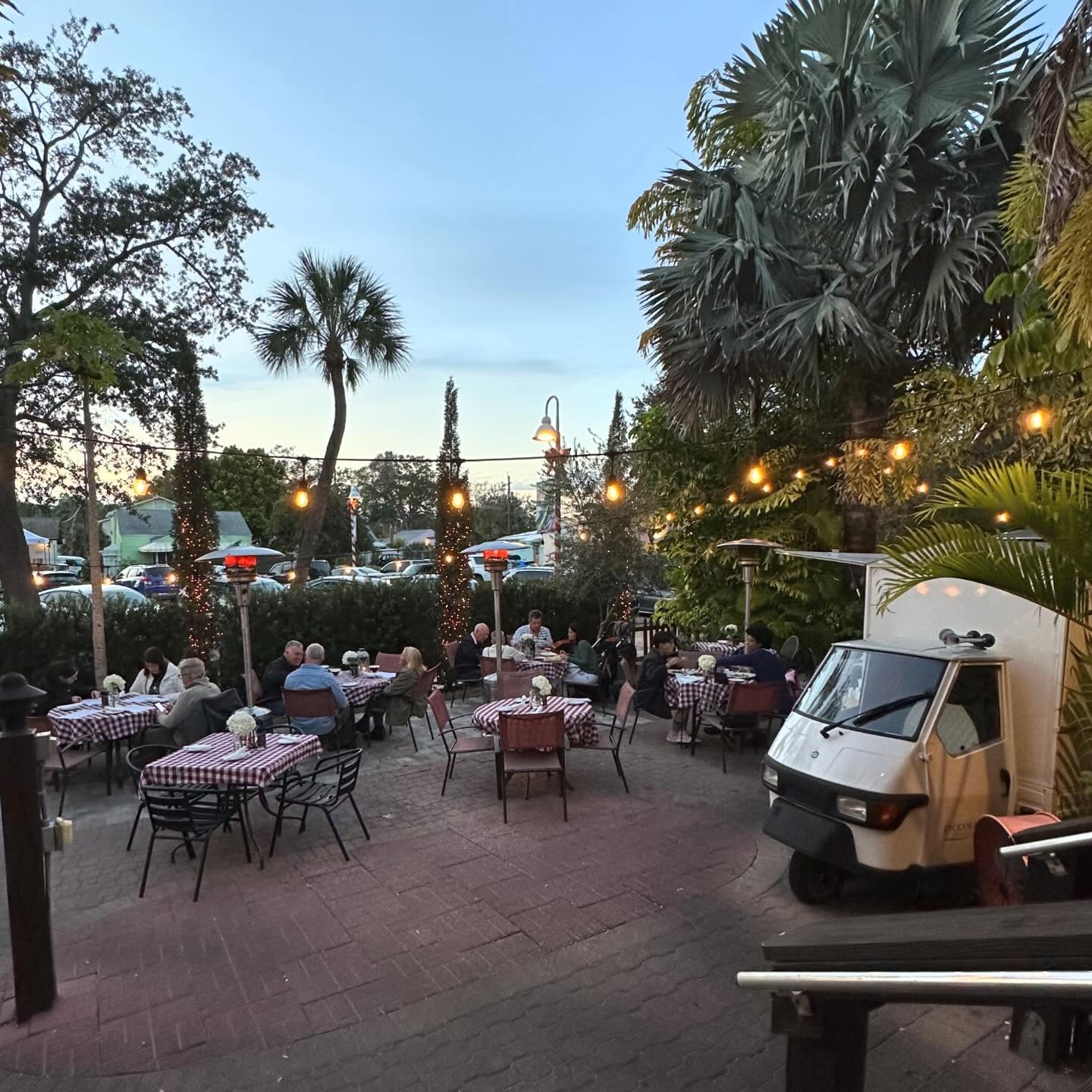 Garden tables at dusk under palms and string lights at Pia's Veranda