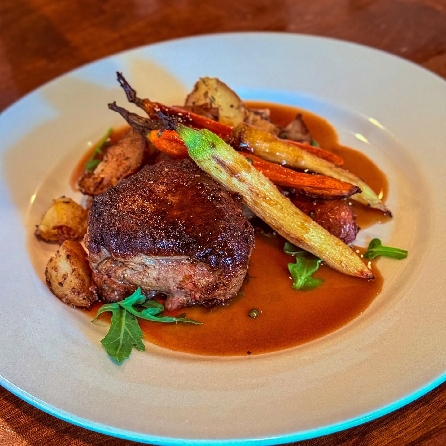 Seared steak with roasted carrots and potatoes, on the Trattoria's dark wood table