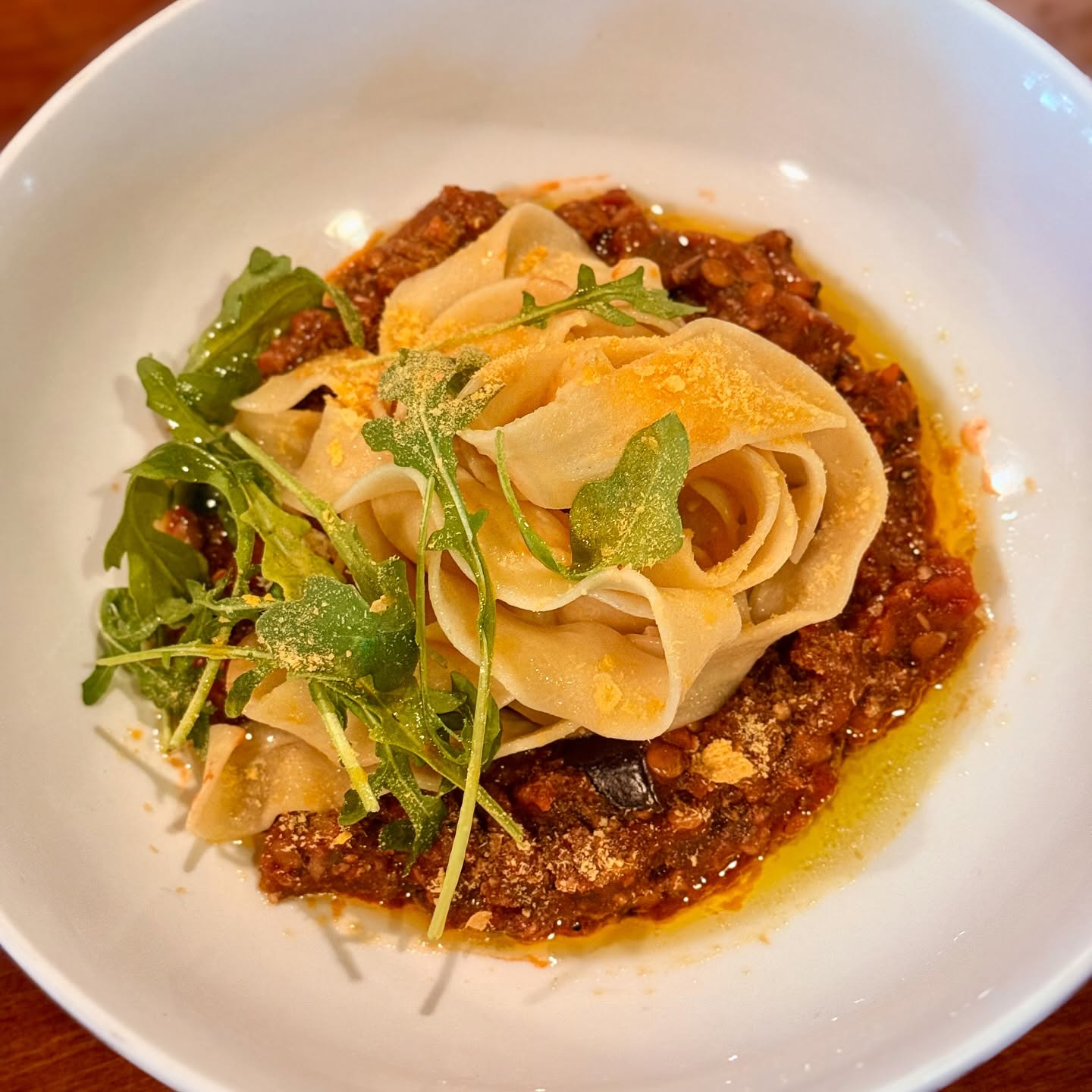 Ribbons of house-made pasta over a meat ragù on a white plate