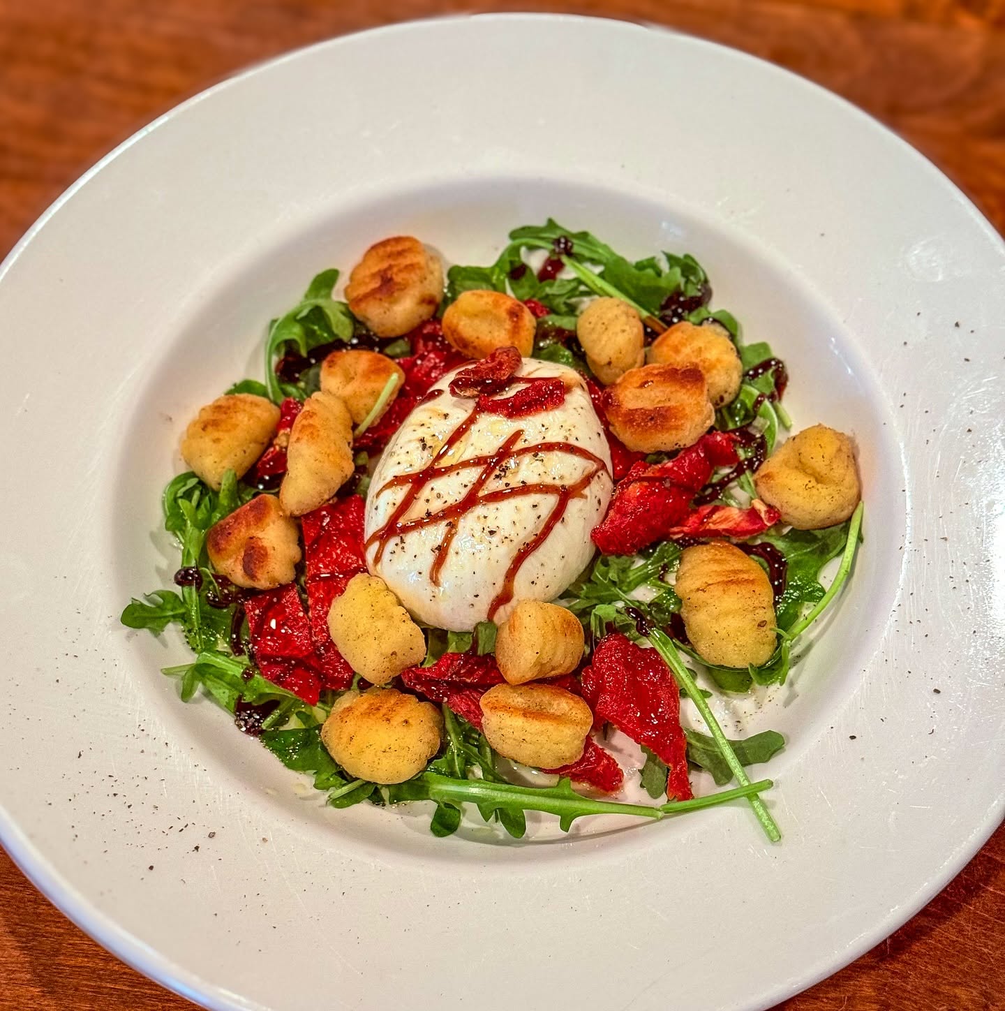 Burrata on arugula surrounded by golden gnocchi and tomatoes